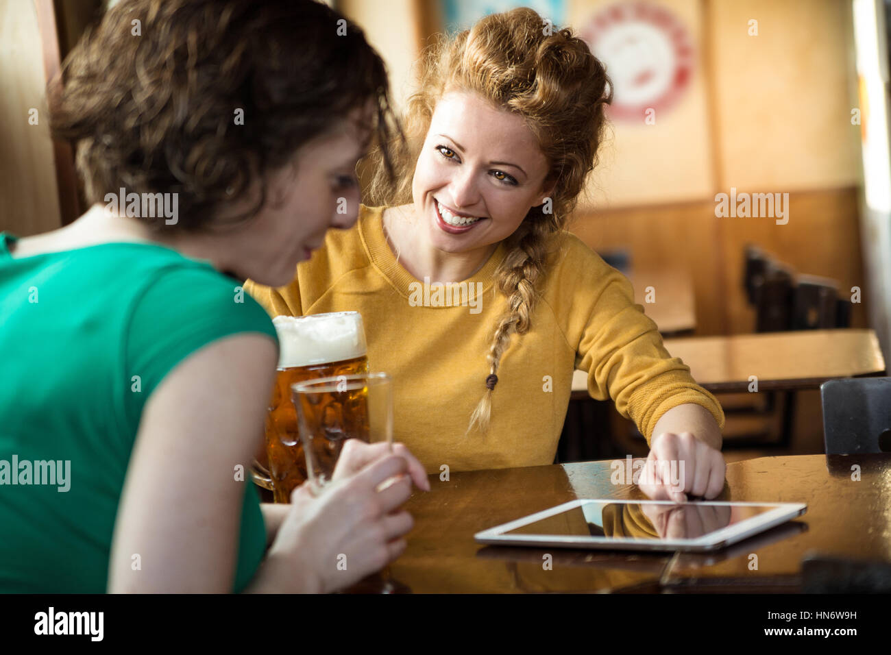 Blond kaukasische Mädchen zeigen auf Tablet beim Biertrinken mit einem Freund in einem Pub Stockfoto