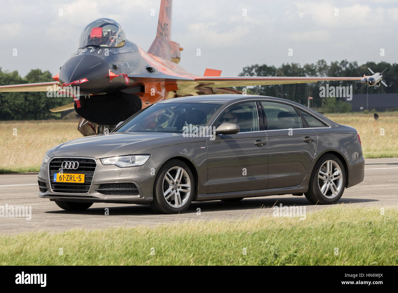 VOLKEL, Niederlande - 15. Juni 2013: Audi A6 Limousine fahren vor einem niederländischen f-16 Kampfjet während der königlichen niederländischen Luftwaffe Tag der offenen Tür. Stockfoto