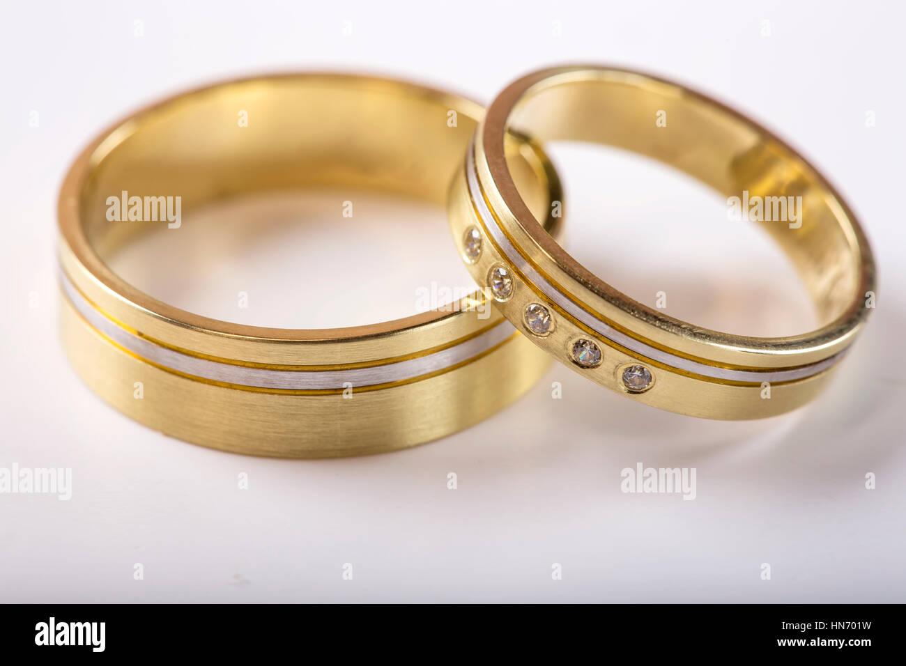 Zwei goldene Hochzeit Ringe auf weiße Oberfläche mit Reflexion Stockfoto
