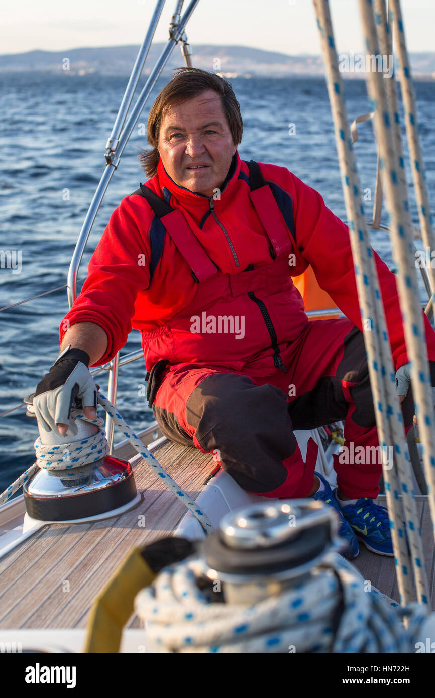 Ein Mann im roten Overall auf einer Segelyacht auf dem Meer. Stockfoto