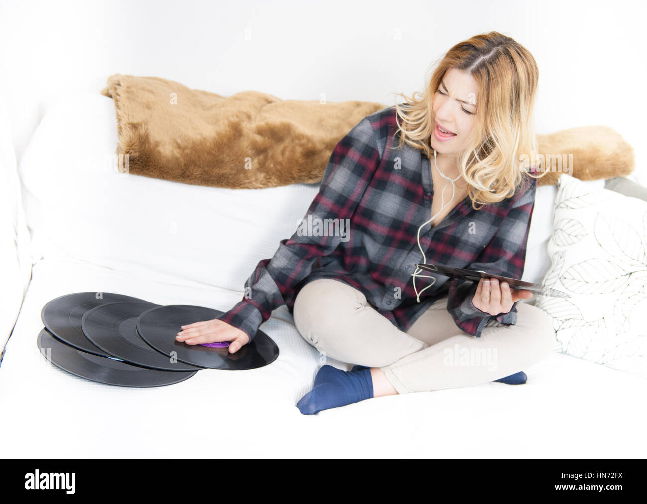 Junge blonde Frau glücklich genießen Musik hören von Vintage Vinyl-Schallplatten auf Sofa im Wohnzimmer Stockfoto