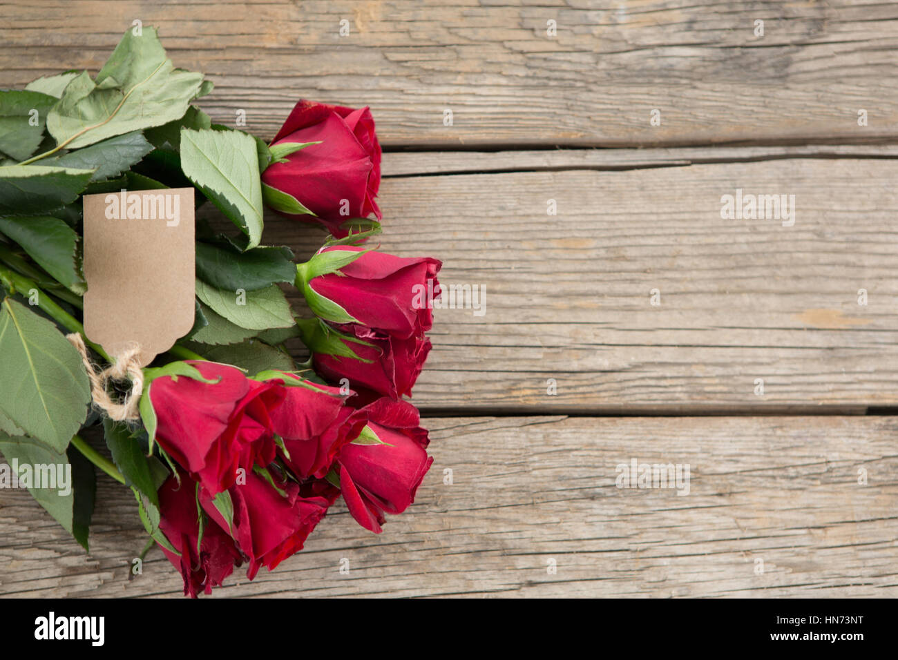 Strauß roter Rosen mit Tag auf hölzernen Hintergrund Stockfoto