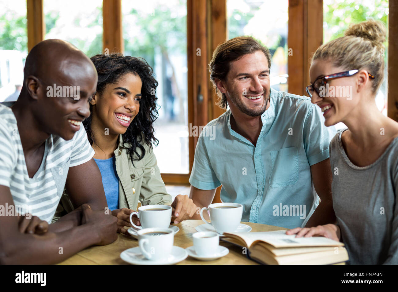 Glückliche Gruppe von Freunden, die Interaktion in CafÃƒÂ © Stockfoto