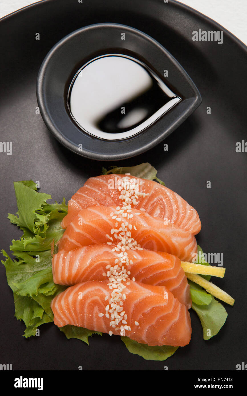 Nahaufnahme von vier Sashimi Sushi mit Sojasauce in schwarze Platte serviert Stockfoto