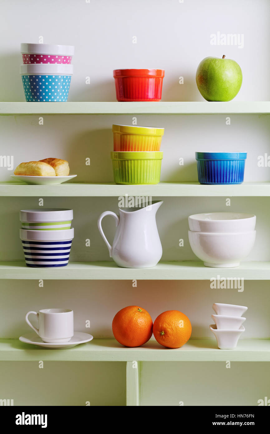 Vielfalt der Keramik im Regal. Bunte Schüsseln, Tassen und weißem Geschirr. Stockfoto