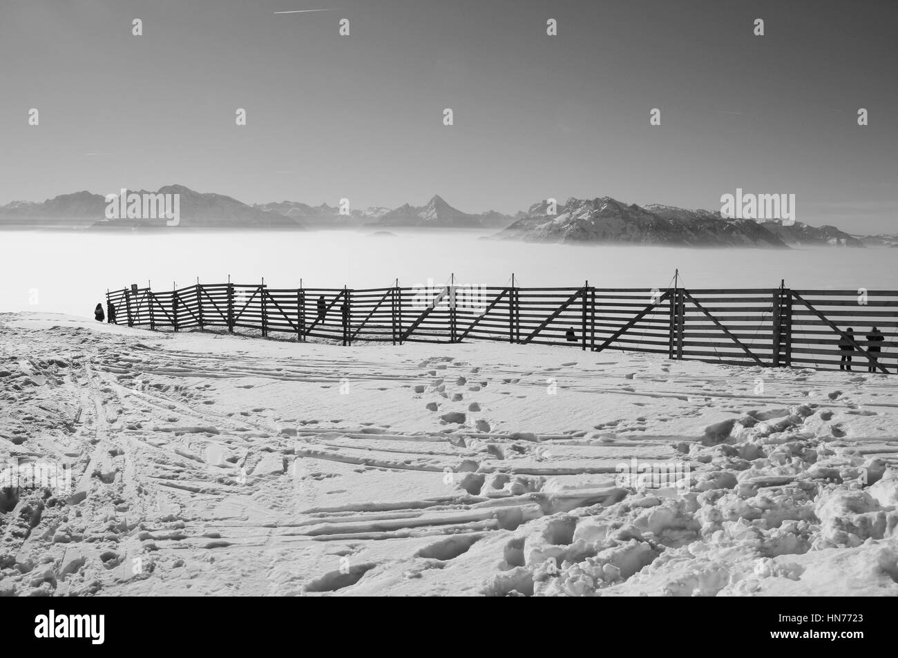 Zaun in den Schnee und Blick auf die von der Spitze des Berges Gaisberg, 1300 m. Eine Schicht von Hochnebel liegt über der Stadt Salzburg. Österreich, Europa. Stockfoto