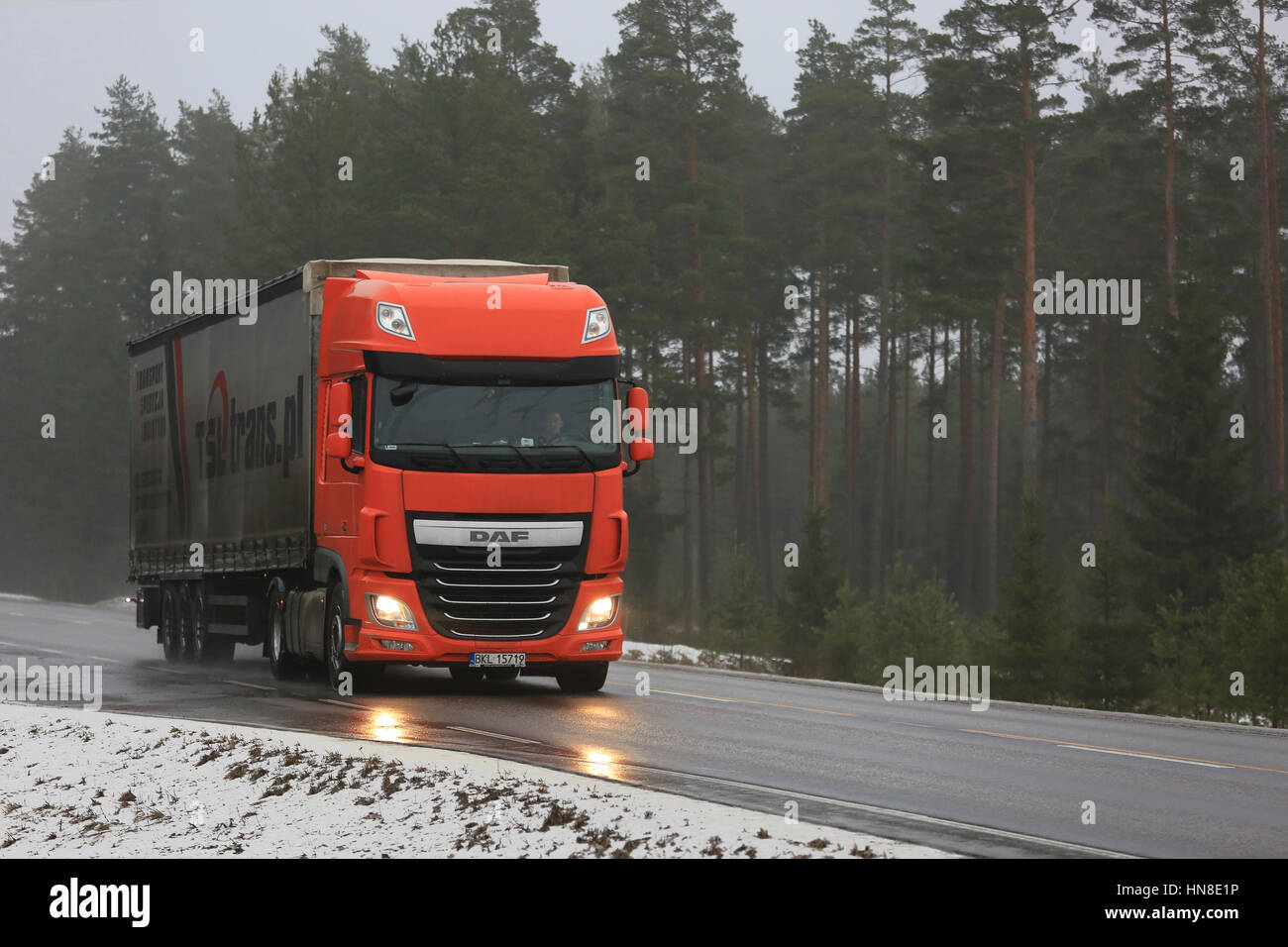 SALO, Finnland - 4. Februar 2017: Orange DAF XF LKW Transporte Sattelanhänger auf nasser Straße an einem nebligen Tag im Winter. Stockfoto