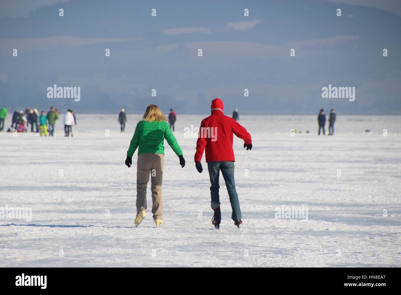 Ein paar ist auf dem Eis Schlittschuhlaufen. Auf dem gefrorenen See Wallersee in Seekirchen, Salzburger Land, Österreich, Europa. Stockfoto