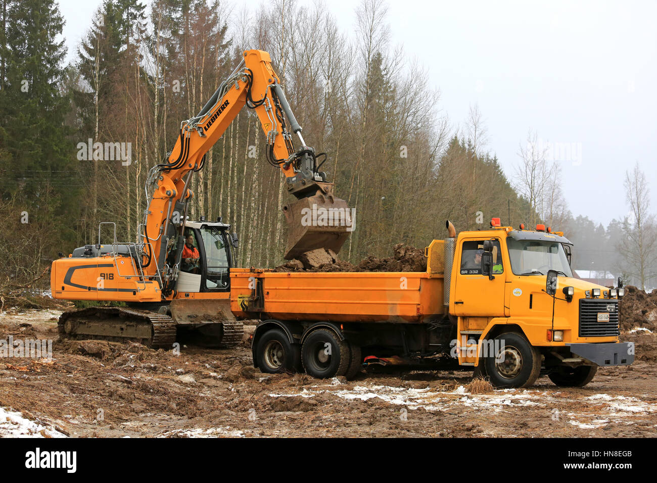 FORSSA, Finnland - 28. Januar 2017: Raupenbagger Liebherr R 918 lädt Boden auf gelben Sisu SR332 Kipp-LKW im Winter. Stockfoto