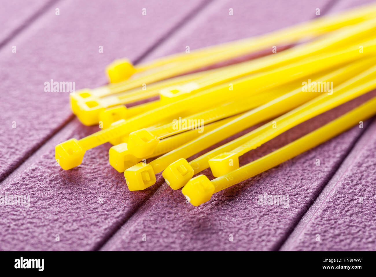Haufen von gelben Kabelbinder auf lila Hintergrund Stockfoto