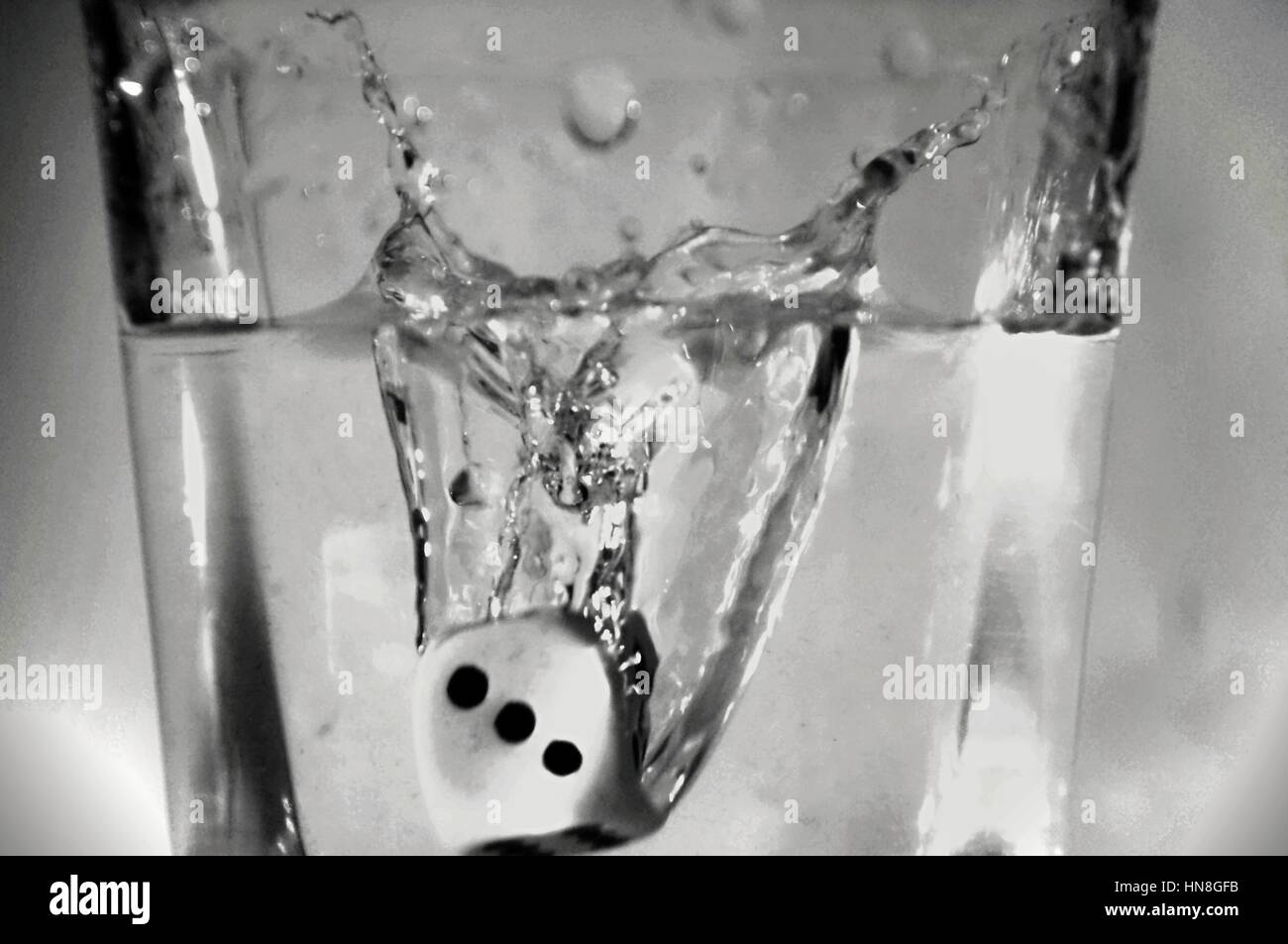 Schwarz eine weiße hohe Geschwindigkeit Foto Würfel springen zu Glas mit Wasser. Stockfoto