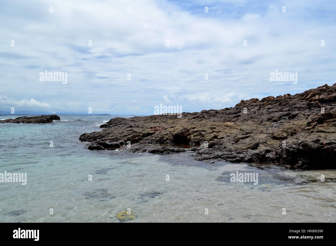 Küstenfelsen im Vordergrund Ozean, Wolken und Horizont im Hintergrund Stockfoto