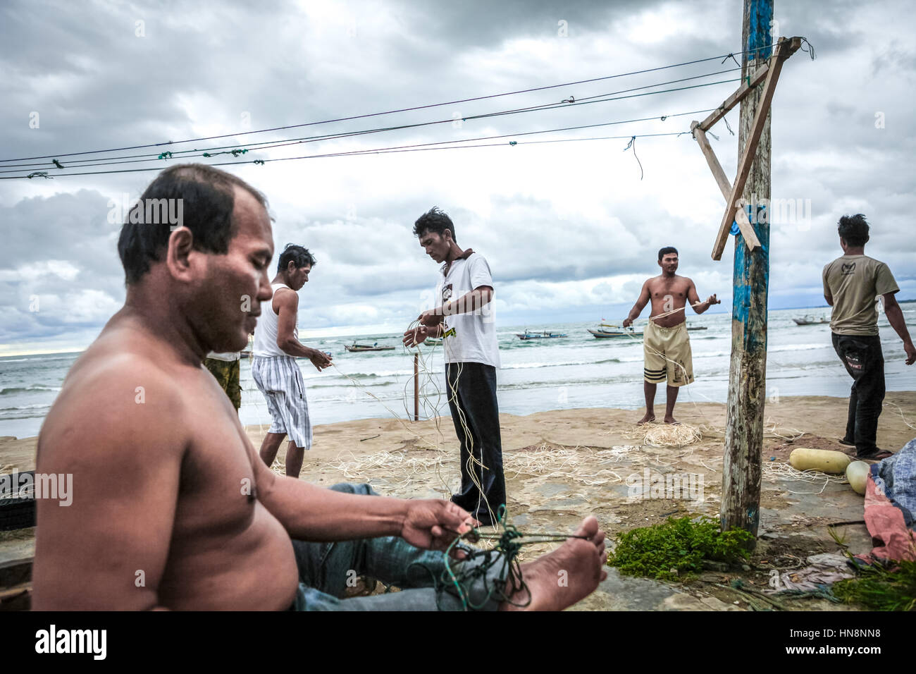Fischer reparieren Angelschnur am Strand des Malabro-Dorfes in Bengkulu, einer Stadt an der Westküste Sumatras mit Blick auf den Indischen Ozean. Archivbild. Stockfoto