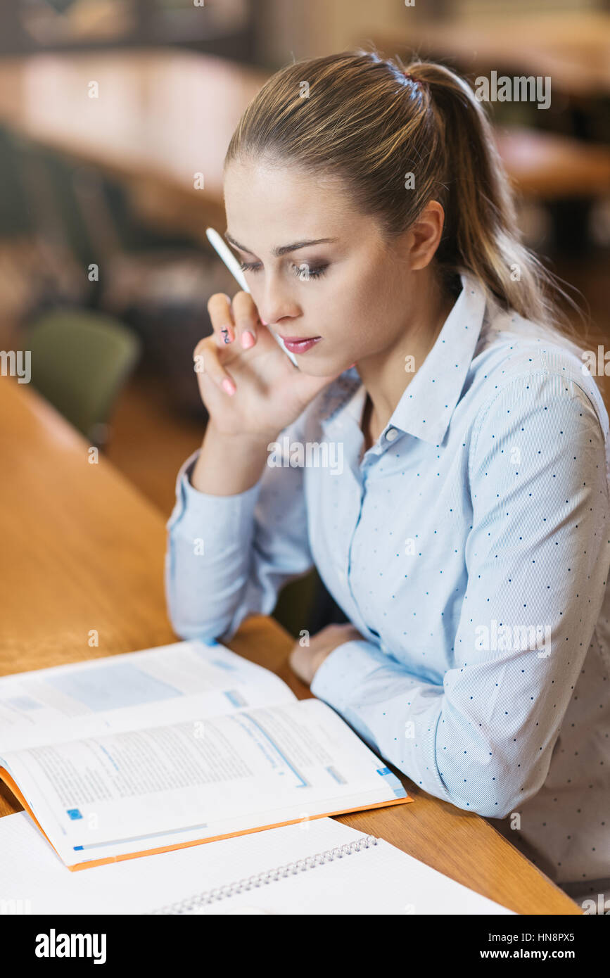 Effiziente Studentin in der Bibliothek, sitzt sie am Schreibtisch und Studium, Ausbildung und Selbstverbesserung Konzept Stockfoto