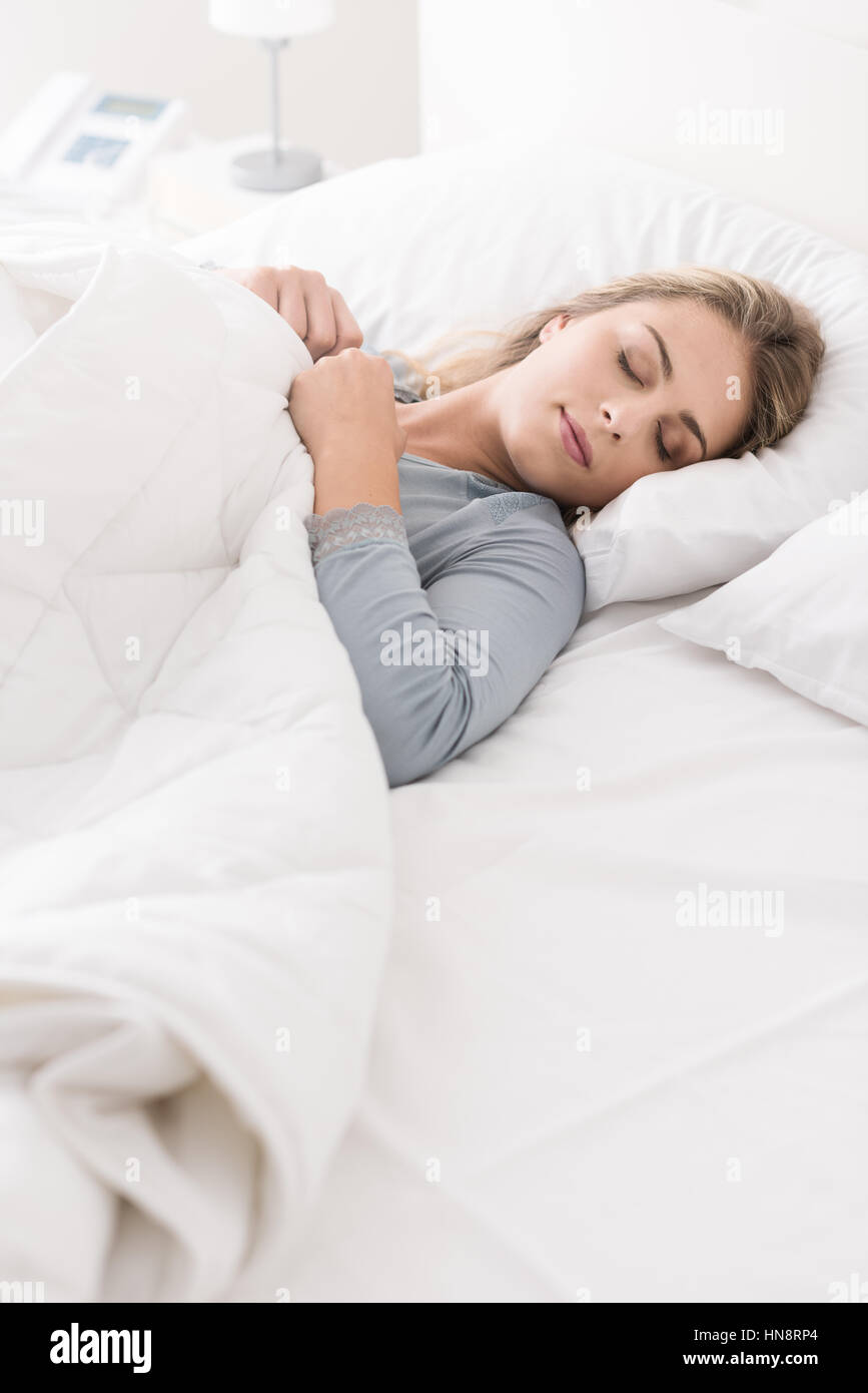 Junge schöne Frau schlafend im Bett, sie ist entspannend und träumen mit geschlossenen Augen, sie deckt sich mit einer weichen Decke Stockfoto