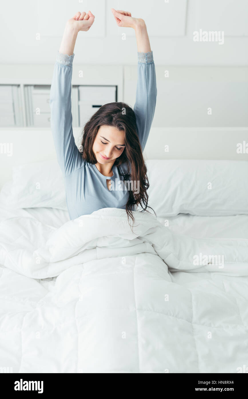 Schöne Frau aufwachen in ihrem Bett im Schlafzimmer, sie dehnen und lächelnd Stockfoto