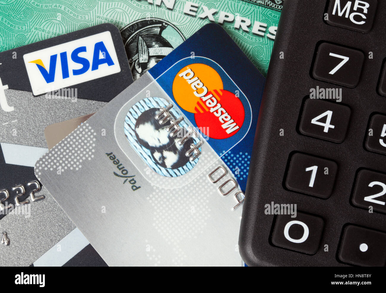 Nahaufnahme von Kredit-und Debitkarten ausgestellt von drei großen Marken VISA, American Express und MasterCard mit einem Taschenrechner Stockfoto