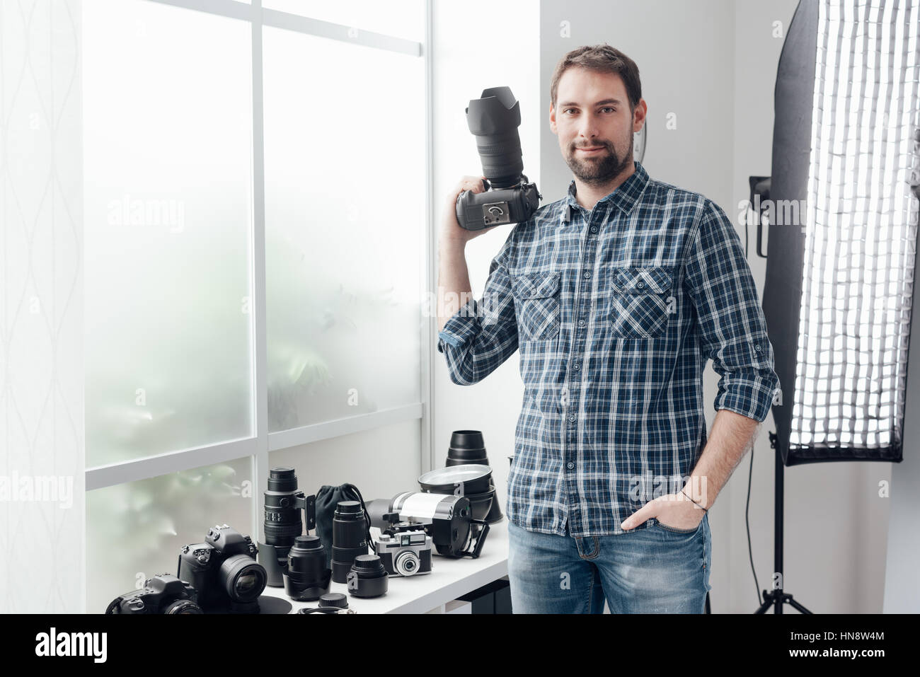 Fotograf in seinem Atelier, posiert er mit seiner Dslr-Kamera und seine professionelle Fotoausrüstung Stockfoto
