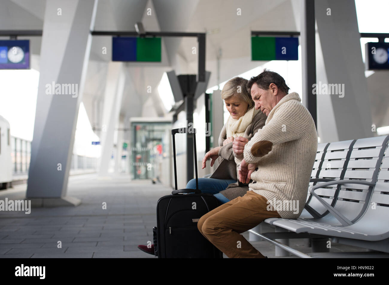 Älteres Paar warten am Bahnhof, Blick auf Uhr. Stockfoto