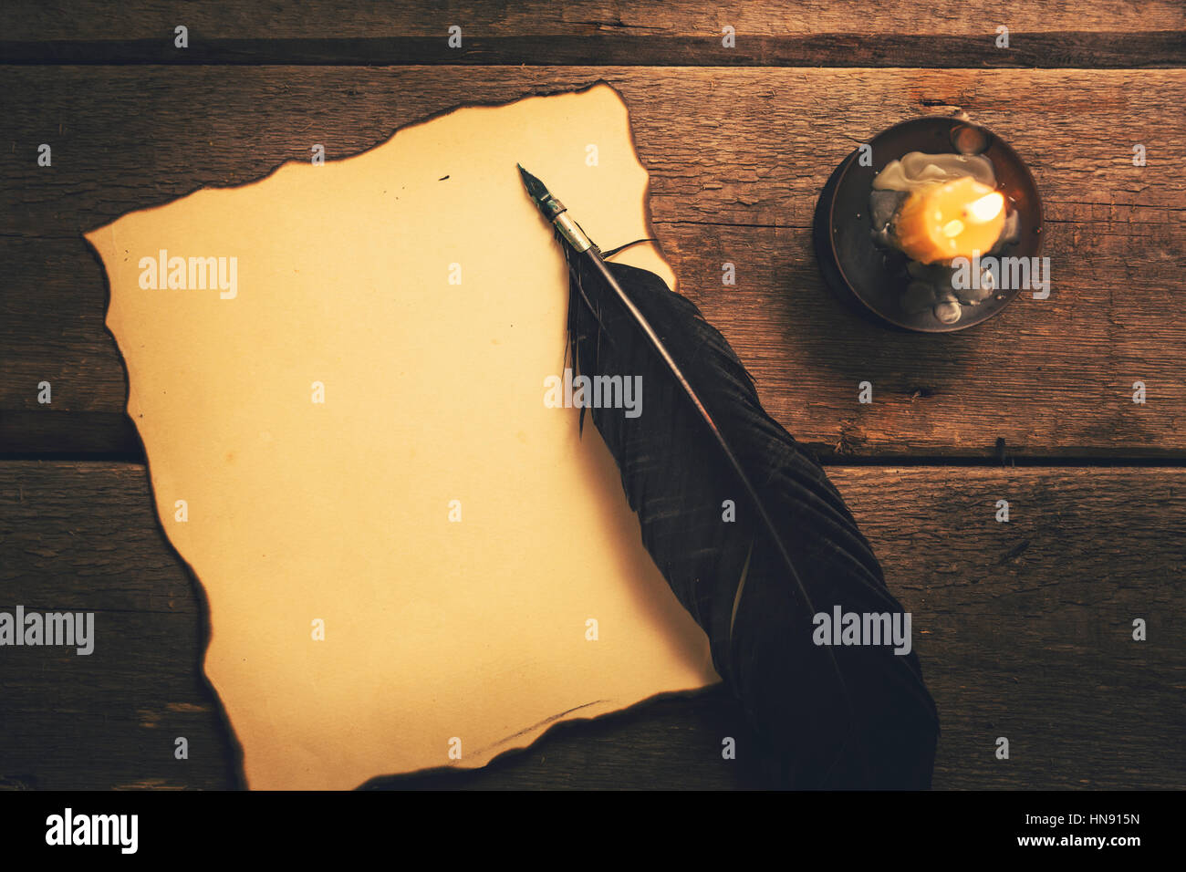 Vintage Feder Stift und alte Blankopapier im Kerzenlicht auf dem Tisch Stockfoto