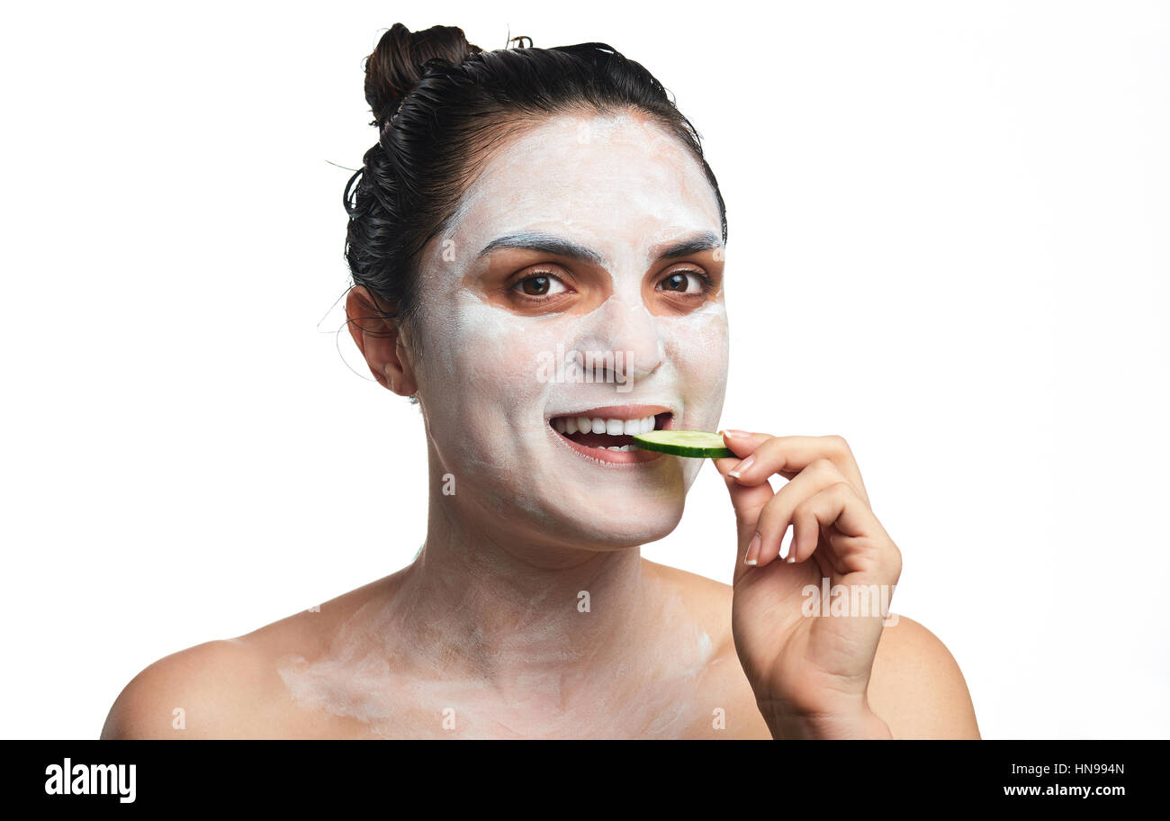Frau Biss Gurke mit Gesichtsmaske isoliert auf weiss Stockfoto