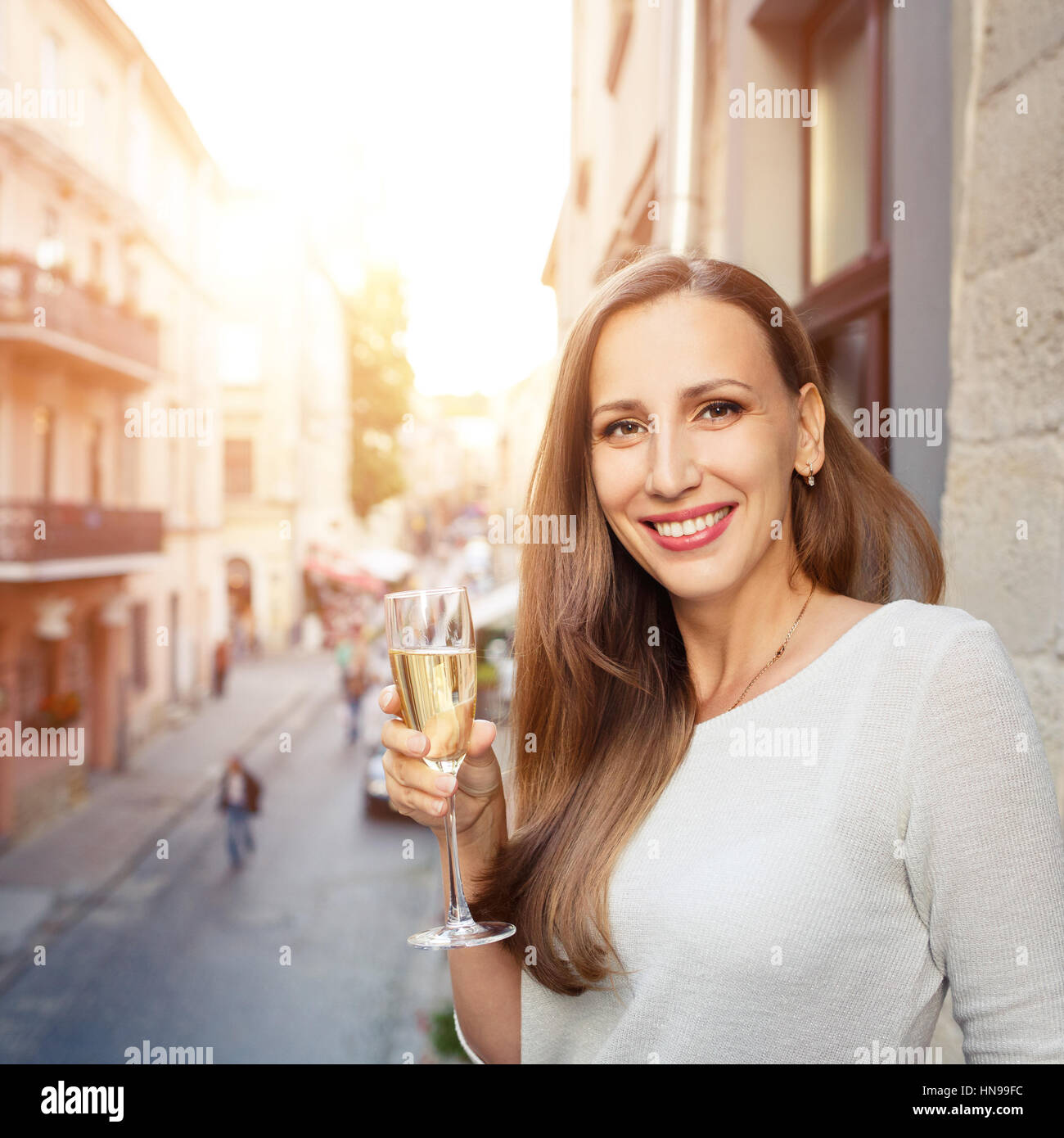 Junge schöne glückliche Frau stehend mit Glas Champagner auf Balkon im freien Stockfoto