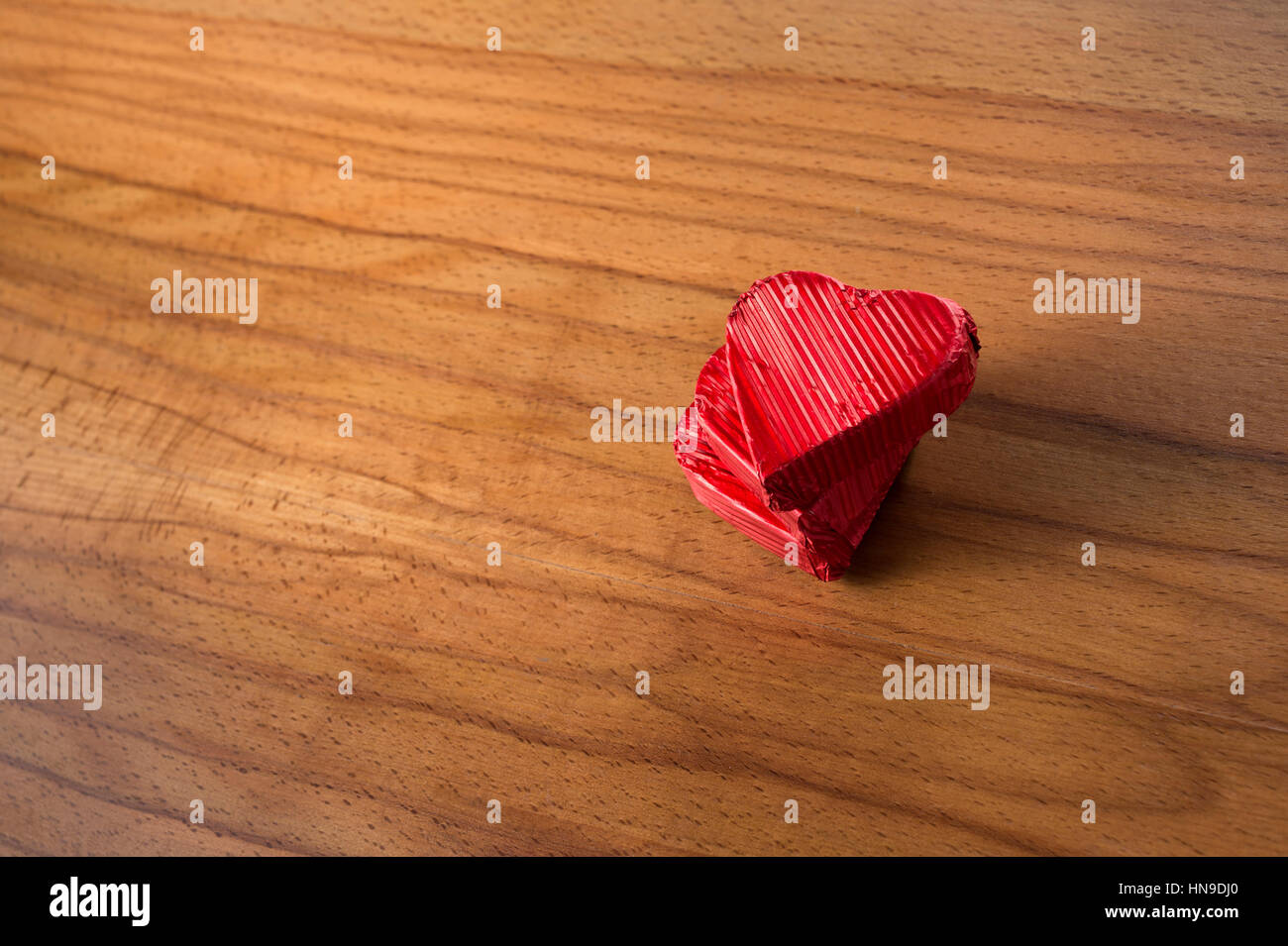Herzförmige und rote Folie verpackt Schokolade auf einem hölzernen Hintergrund. Stockfoto