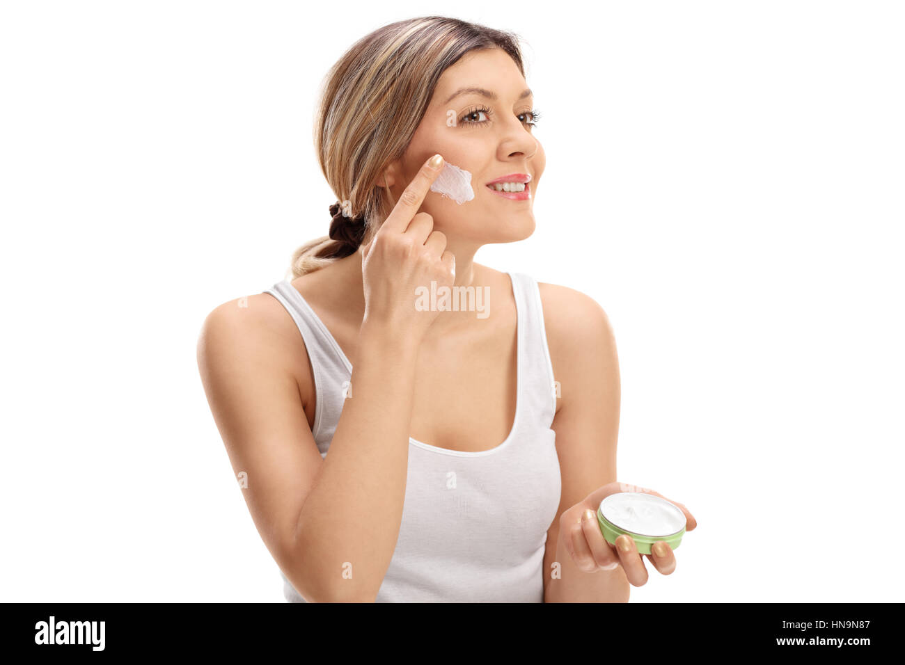 Hübsche Frau auftragen Hautcreme im Gesicht isoliert auf weißem Hintergrund Stockfoto