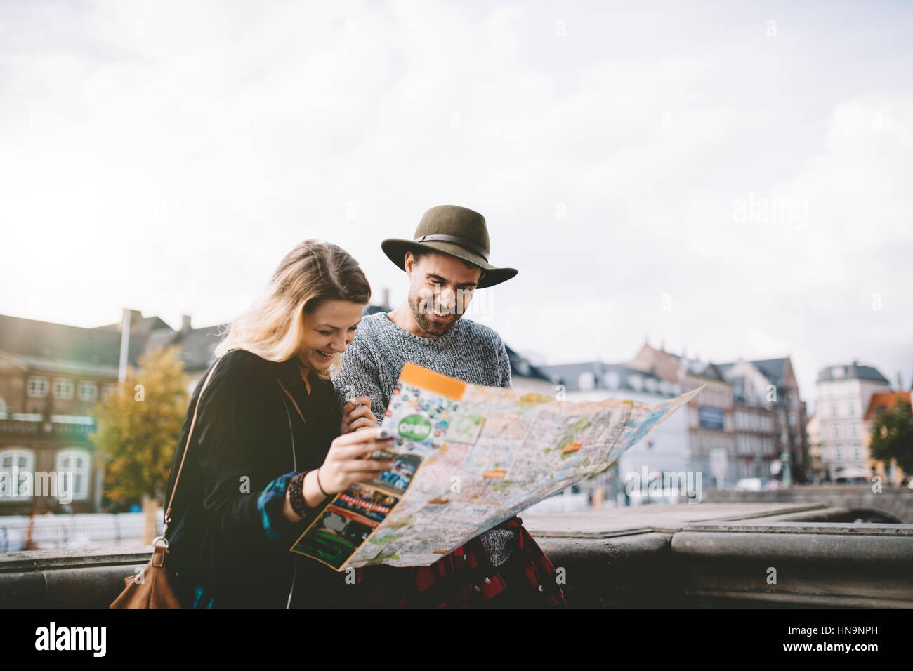 Glückliches junges Paar betrachten einer Navigationskarte. Touristischen paar stehen an der Straße an einem bewölkten Tag eine Karte suchen. Stockfoto