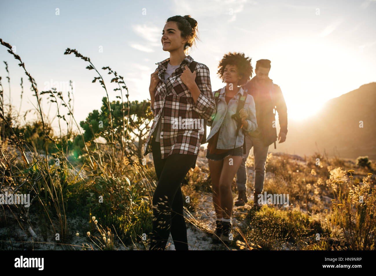 Gruppe von Freunden auf Land zu Fuß an einem Sommertag. Junge Menschen wandern in der Landschaft. Stockfoto