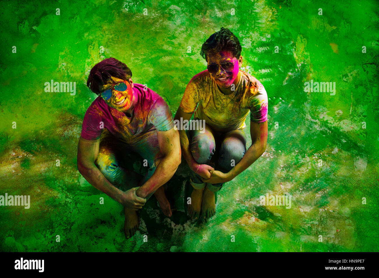 Erhöhte Ansicht der jungen indischen Männer sitzen, während Holi Farbe Festival in Farbpulver abgedeckt. Stockfoto