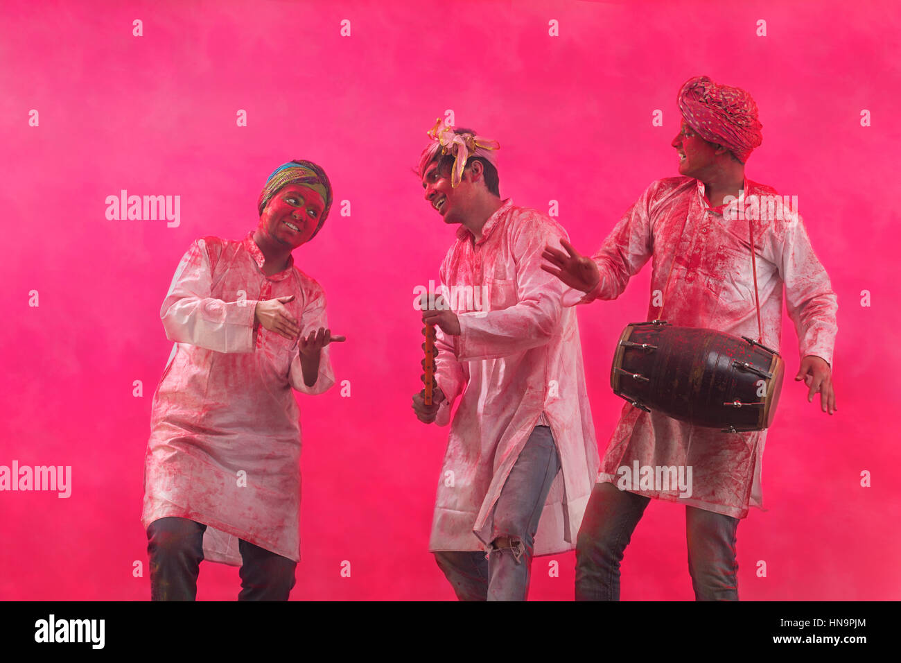 Drei junge indische Männer mit farbigen tanzen während Holi Flächenfarbe festival Stockfoto