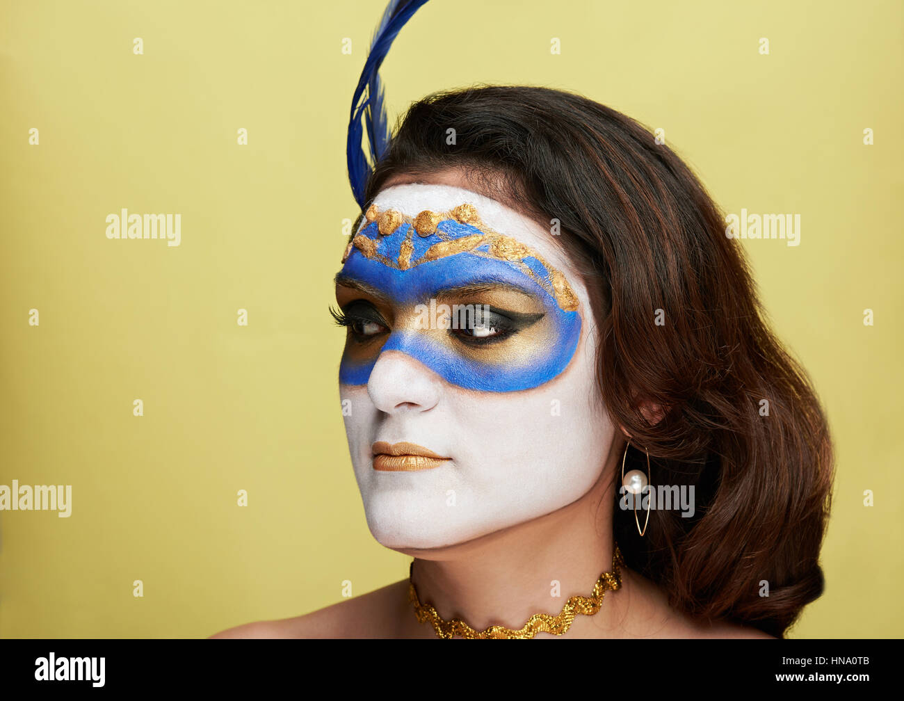 Frauen suchen auf Seite mit bemalten Maske auf gelbem Hintergrund Stockfoto