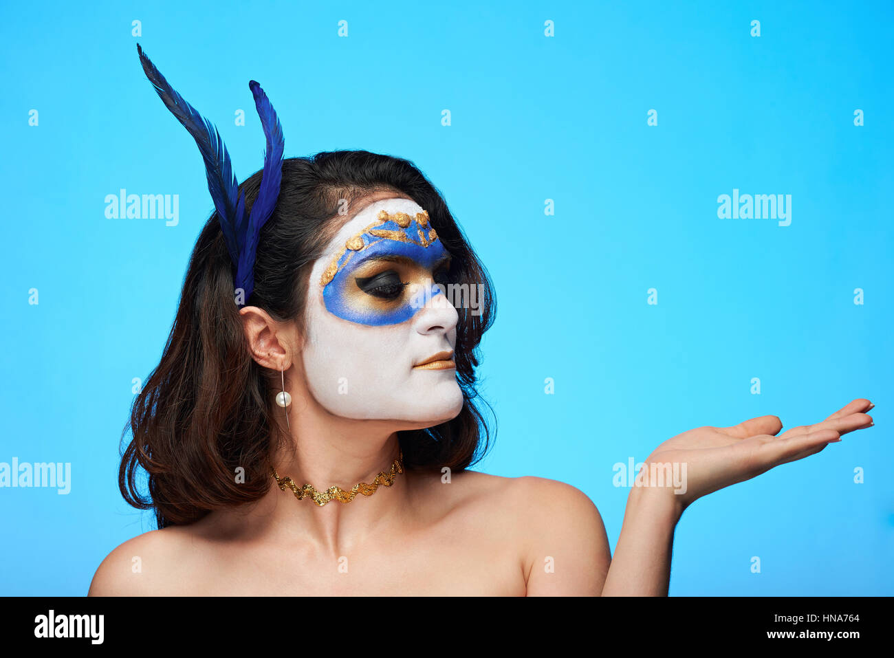 Frau Blick auf ihre flache Hand auf blauem Hintergrund isoliert Stockfoto