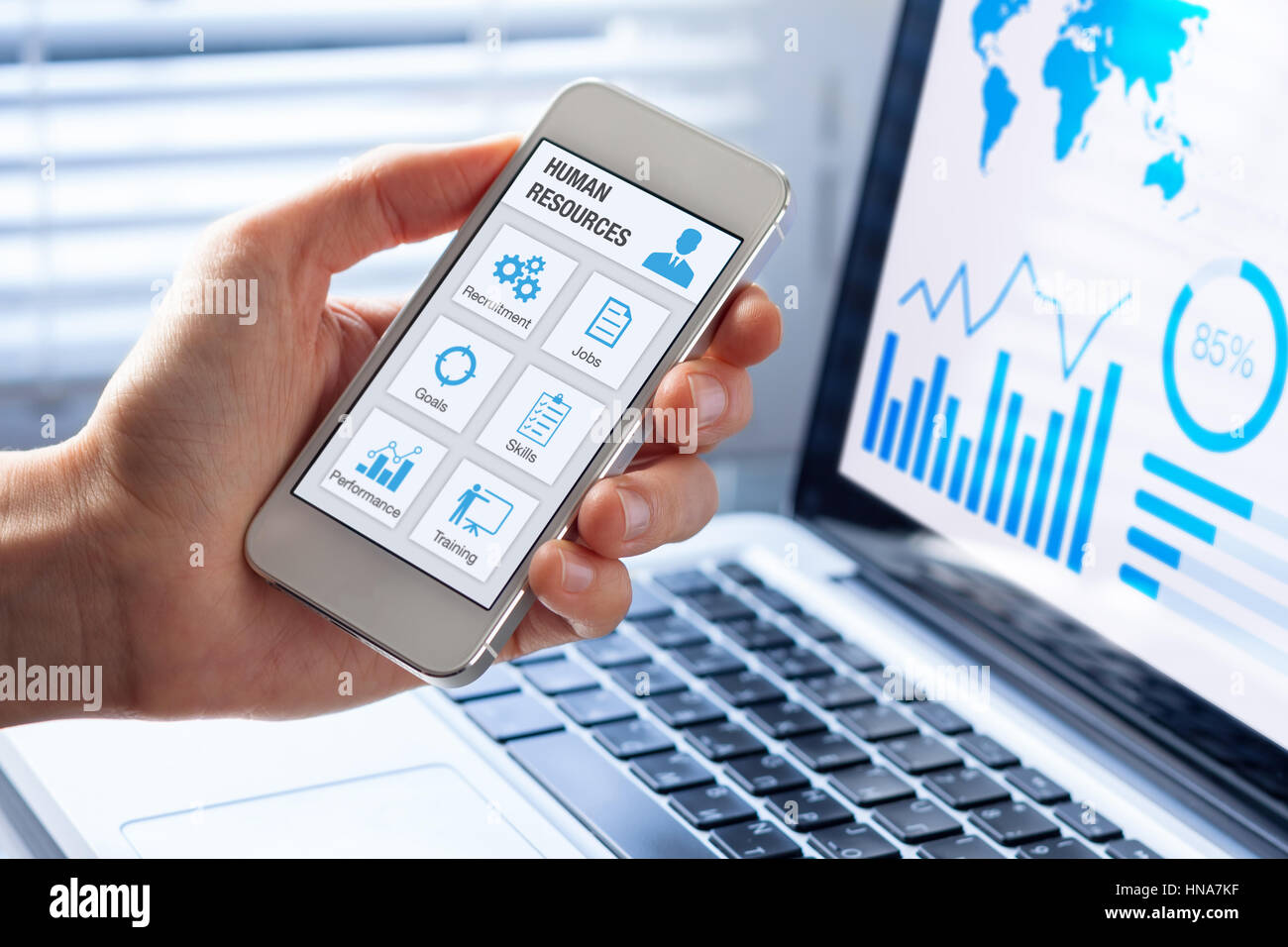 Human Resources (HR) Management app-Konzept auf einem Handy-Bildschirm mit einer Person Hand und Büro innen Hintergrund, Symbole über die Einstellung Einstellung Stockfoto