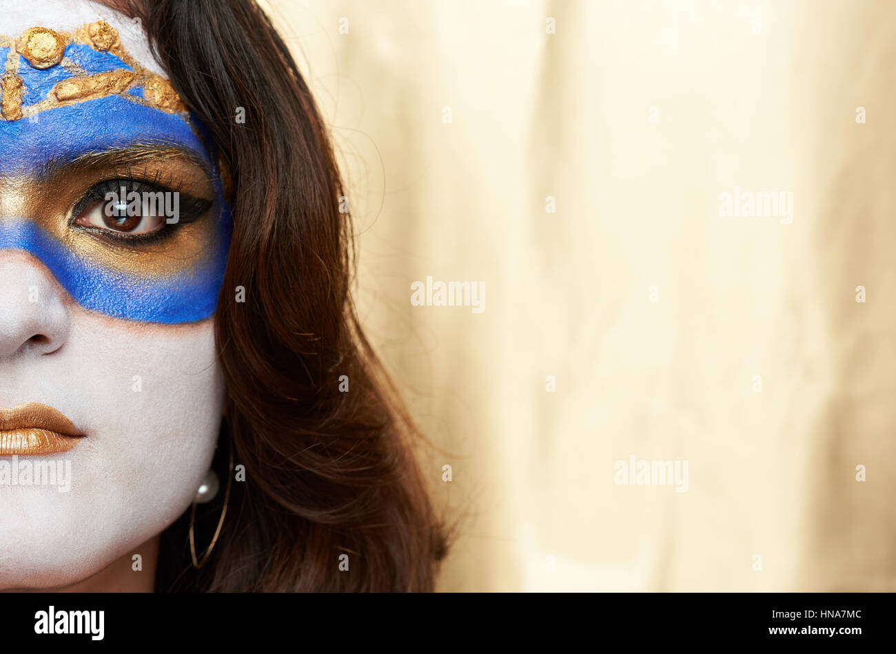 halb bemaltem Gesicht gold Maske auf goldenem Hintergrund Stockfoto