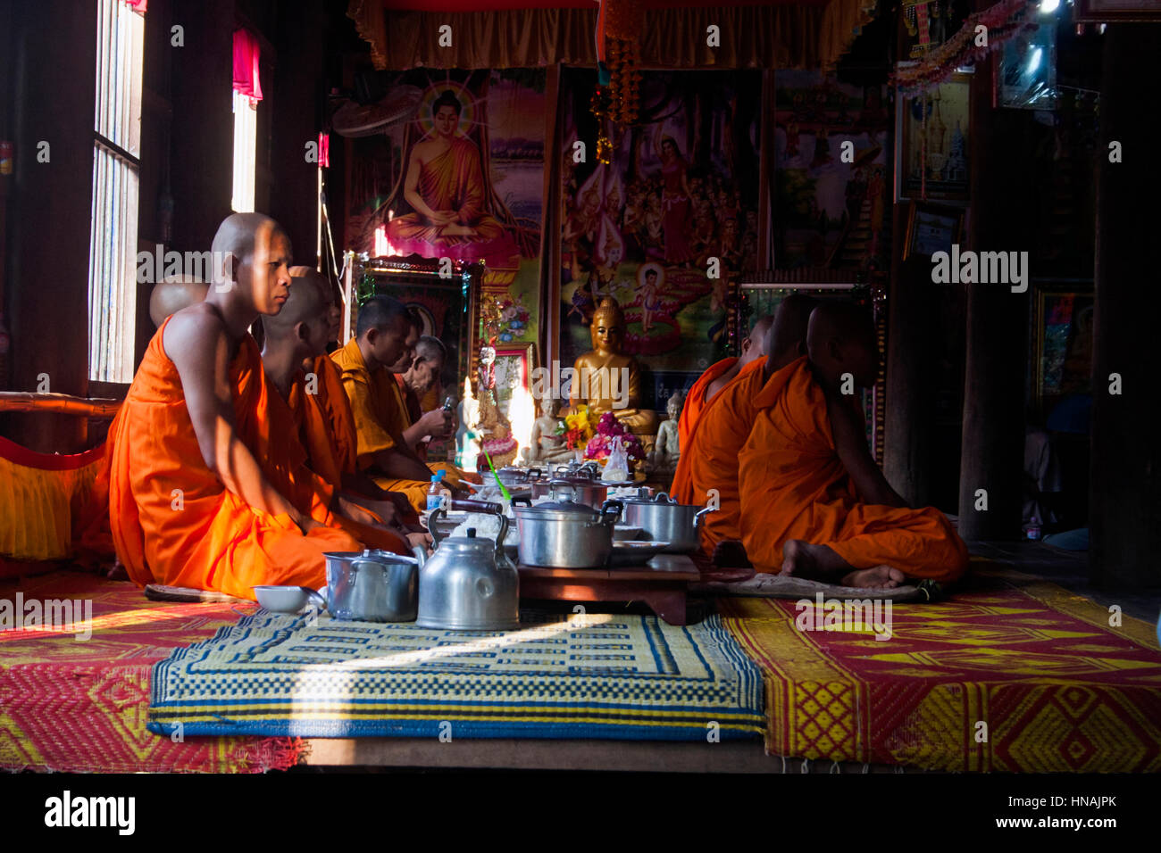 Buddhistische Mönche tragen orangefarbene Gewänder sitzen auf dem Boden im Inneren einer Pagode während einer buddhistischen Zeremonie in Chork Village, Kambodscha. Stockfoto