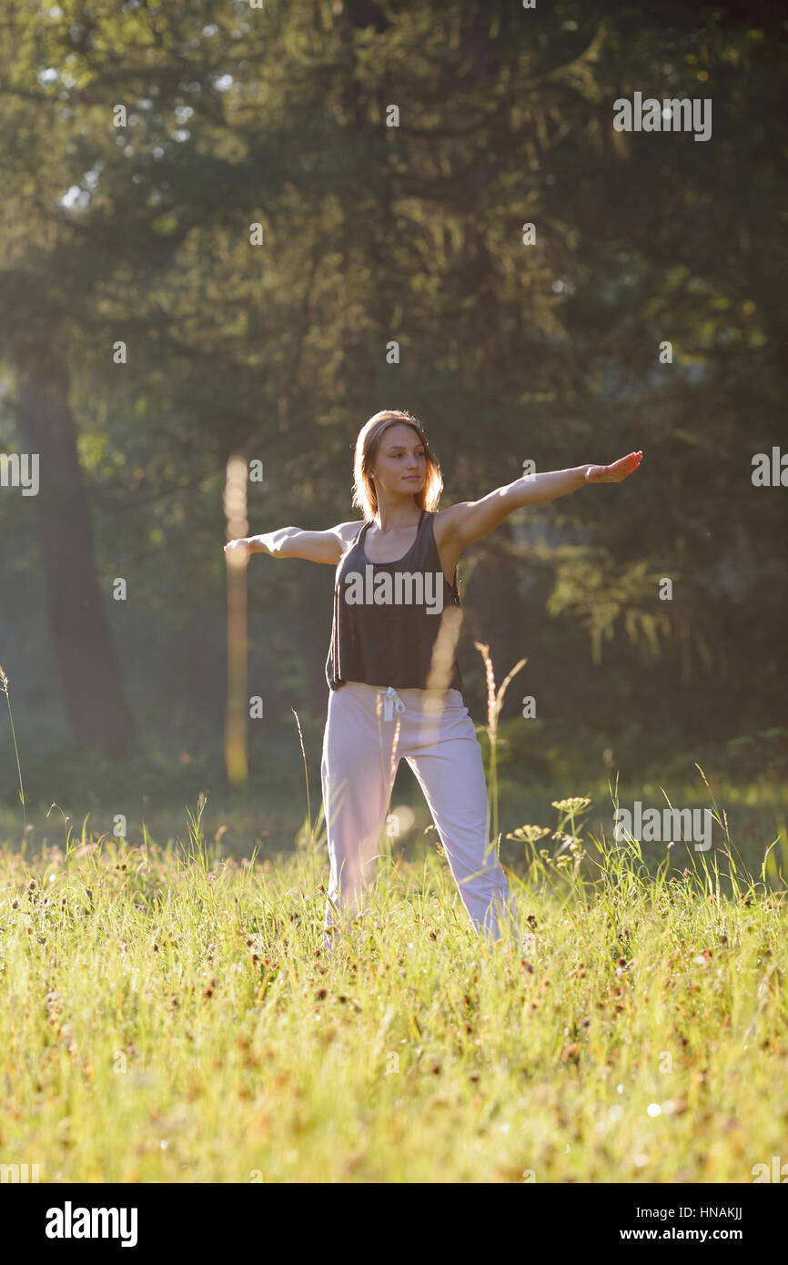 Mädchen Smilling und Praktiken Yoga im park Stockfoto