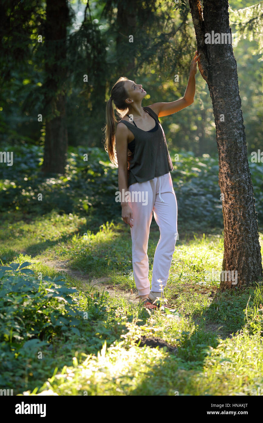 Schöne Mädchen berühren Holz im geheimnisvollen Wald Stockfoto