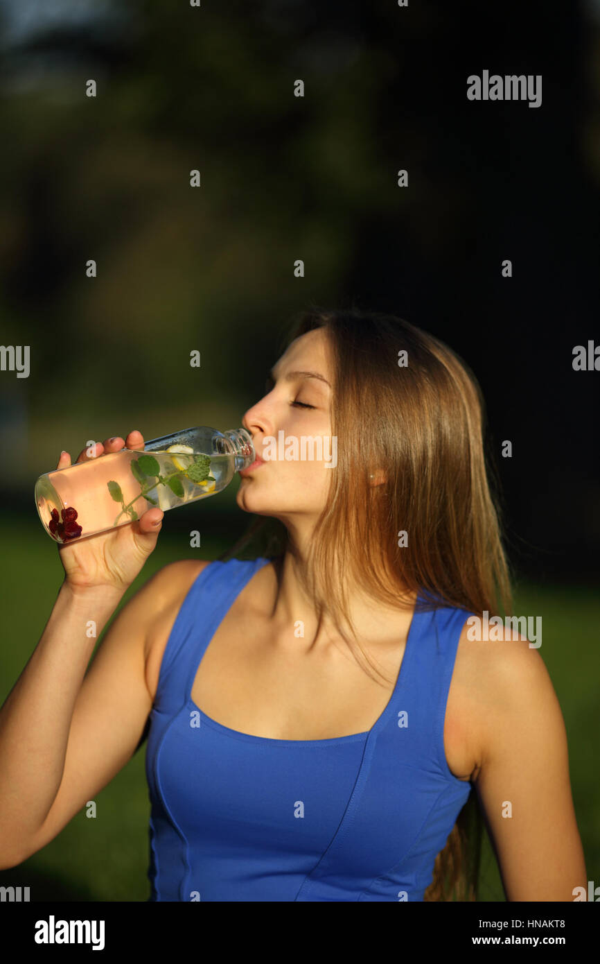 Schöne junge Frau, die Entgiftung Trinkwasser mit, Zitronenminze und Himbeeren Stockfoto