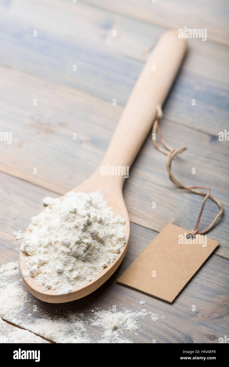 Haufen von weißes Mehl in Holzlöffel auf Tisch mit Label für Text. Stockfoto