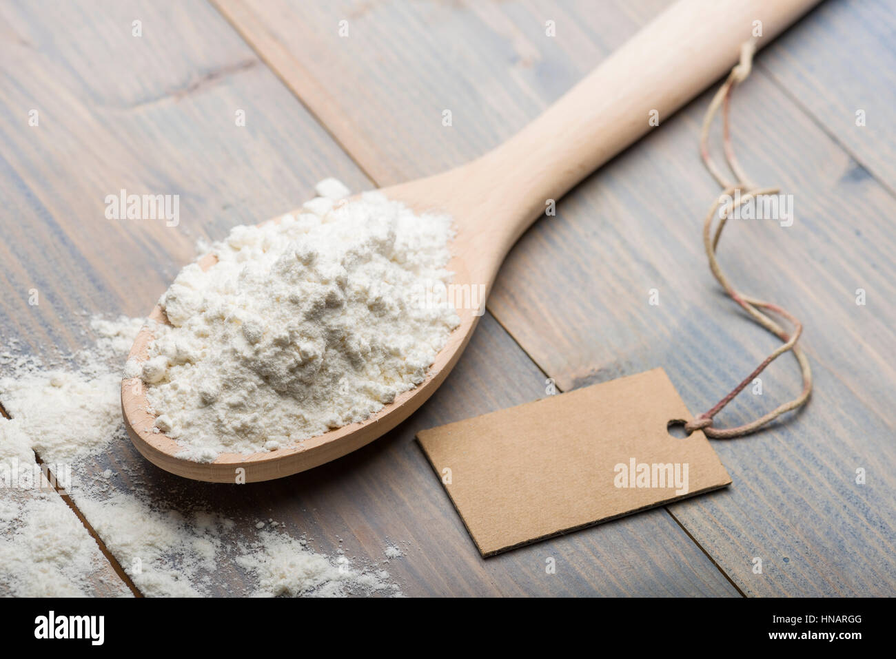 Haufen von weißes Mehl in Holzlöffel auf Tisch mit Label für Text. Stockfoto