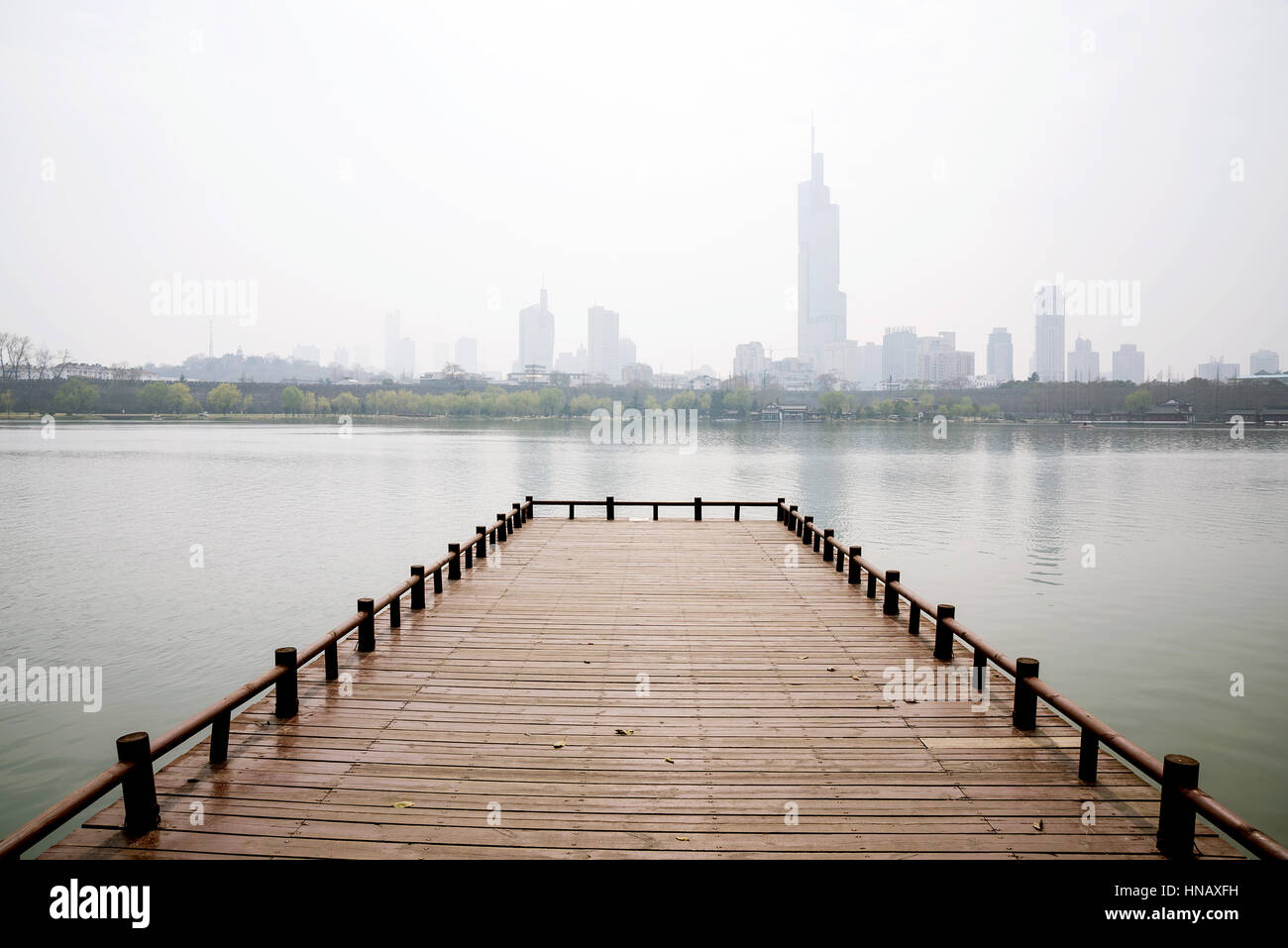 Am See Pier auf Xuanwu See mit Stadtgebäude im smog Stockfoto