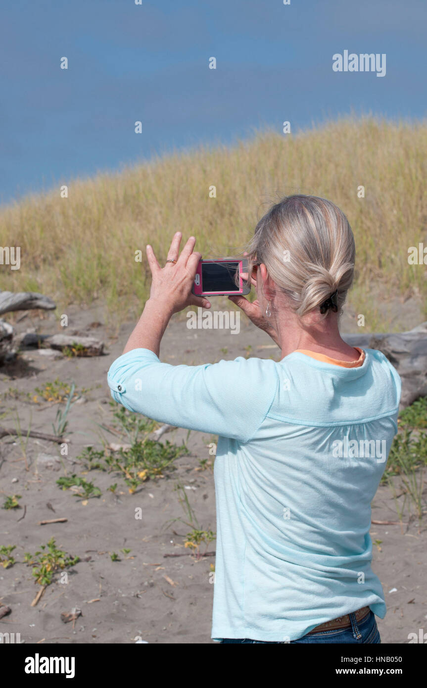 Eine weibliche Fotografiert am Strand mit ihrem Handy an der Doppel Häfen State Park in West Port, WA, USA Stockfoto