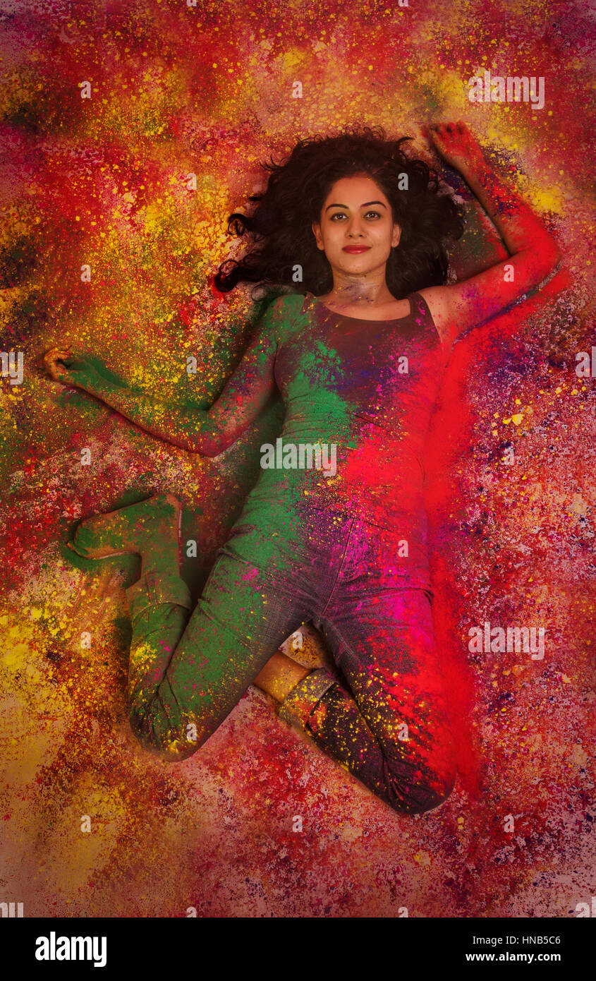 Erhöhte Ansicht eines indischen Mädchens liegend und mit Farbpulver während Holi Farbe festival Stockfoto