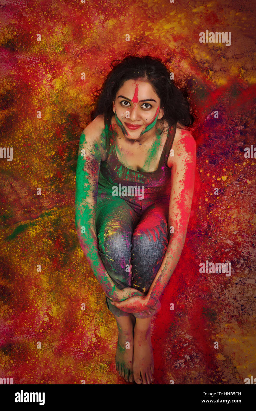 Erhöhte Ansicht eines indischen Mädchens sitzen, während Holi Farbe Festival in farbigen Pulver bedeckt Stockfoto