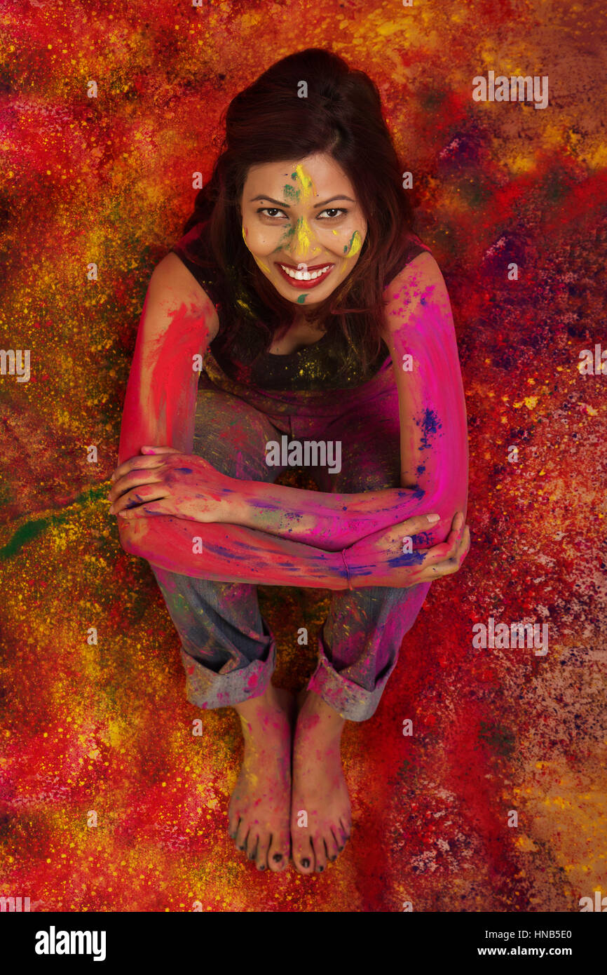 Erhöhte Ansicht eines indischen Mädchens sitzen, während Holi Farbe Festival in farbigen Pulver bedeckt Stockfoto