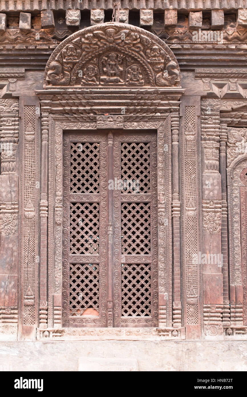 Reich geschnitzte Lattic-Arbeit Holztür eines alten Hauses, mit einem hölzernen Türsturz geschnitzt mit Hindu-Gottheiten in Bhaktapur, Kathmandu Stockfoto