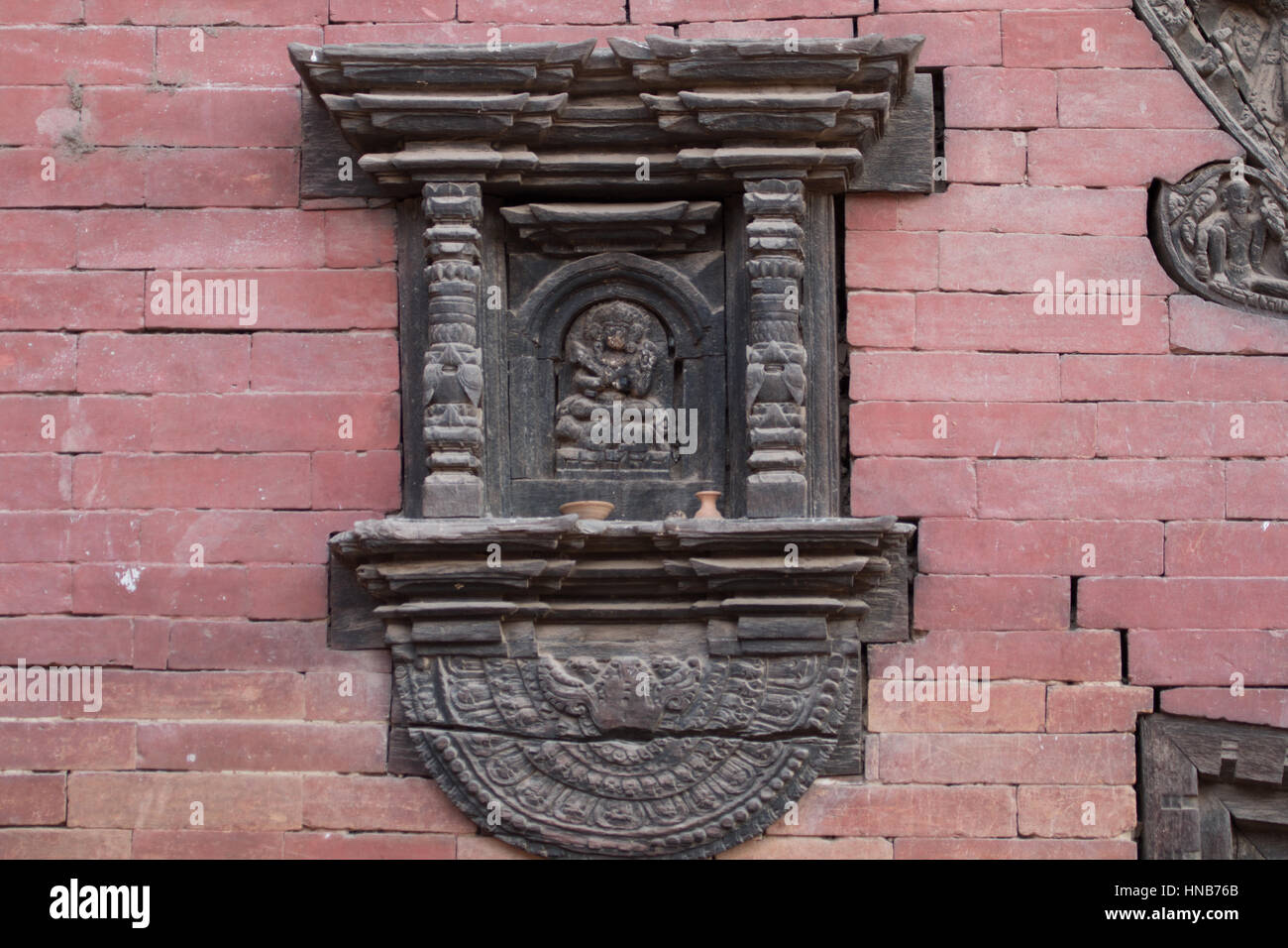 Holz-Schnitzerei der Hindu-Gottheit eingefügt in das äußere eines Gebäudes in Bhaktapur, Kathmandu, als Schutz und Schrein Stockfoto