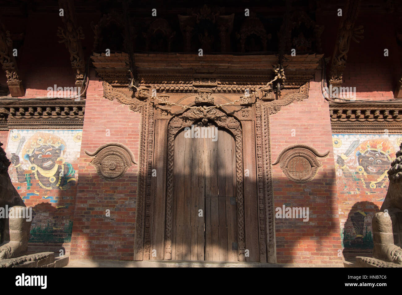 Kunstvoll geschnitzte Holztür und Sturz eines alten Gebäudes in Bhaktapur, Kathmandu mit religiösen Motiven Stockfoto